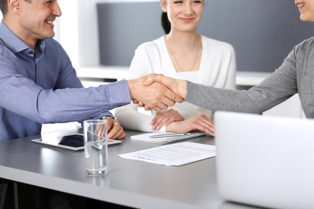 Grupo de empresarios dándose la mano después de discutir preguntas y lograr un acuerdo en una reunión en una oficina moderna. Primer plano de apretón de manos. Trabajo en equipo, asociación y concepto de negocio.