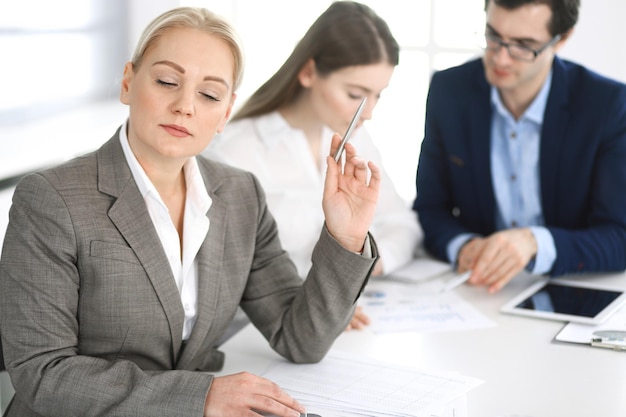 Grupo de empresarios discutiendo preguntas en una reunión en una oficina moderna. Headshot de mujer de negocios en la negociación. Trabajo en equipo, asociación y concepto de negocio.