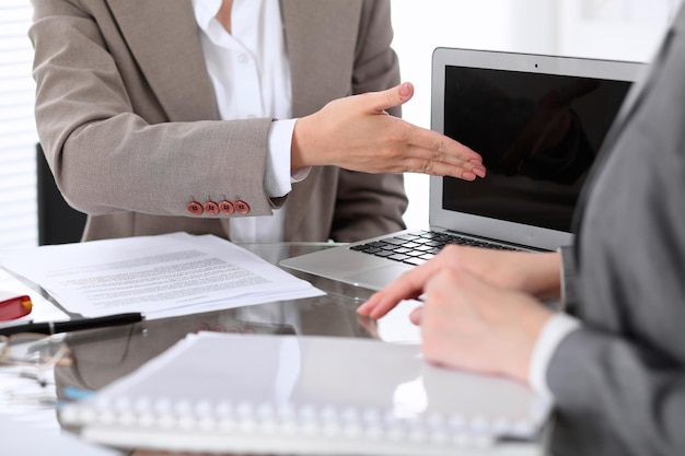 Grupo de empresarios o abogados en reunión discutiendo documentos de contrato Mujer apuntando al monitor de la computadora portátil