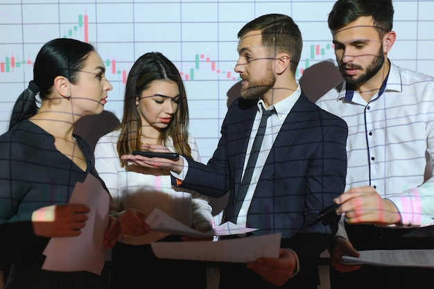 Foto grupo de empresarios que trabajan en la oficina moderna gráfico de precios técnicos gráfico de velas rojas y azules y fondo de pantalla de computadora de comercio de acciones doble exposición comerciantes analizando datos