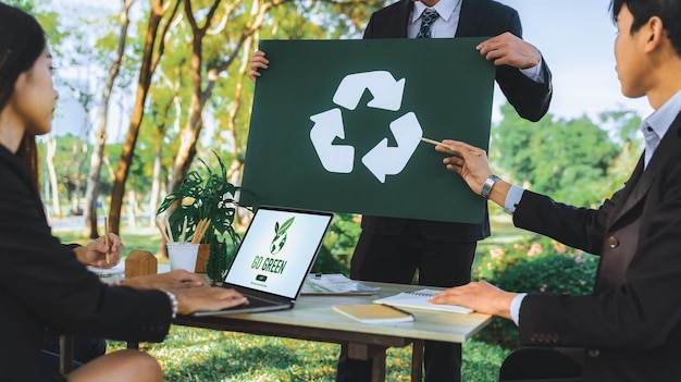 Grupo de empresarios reunidos en una oficina al aire libre en la naturaleza, planificando e intercambiando ideas sobre una estrategia de reciclaje para un medio ambiente más ecológico mediante la reducción y reutilización de residuos reciclables.