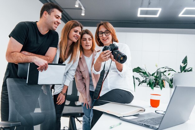 Grupo de empresarios con ropa formal en el interior de la oficina mirando fotos en la cámara