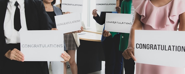 Grupo de empresarios en ropa de negocios sosteniendo pancartas de papel con palabras felicitaciones y mostrar a la cámara. Concepto de saludo y agradecimiento por el éxito en el trabajo o el trabajo en la empresa.