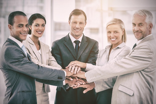 Grupo de empresarios sonrientes juntando sus manos en el lugar de trabajo