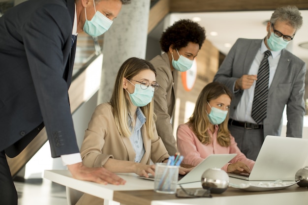 Grupo de empresarios tienen una reunión y trabajan en la oficina y usan máscaras como protección contra el coronavirus