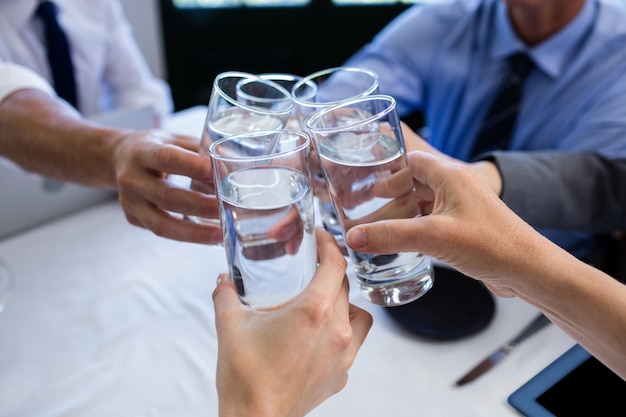 Grupo de empresarios tostado vaso de agua en restaurante.