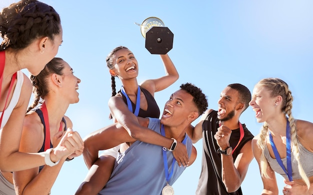 Grupo de un equipo joven y diverso de atletas celebrando su victoria con un trofeo de oro Equipo de atletas felices activos regocijándose después de ganar un premio o trofeo después de una carrera competitiva