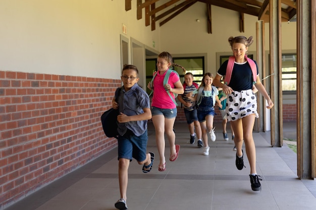 Foto grupo de escolares corriendo en un corredor al aire libre en la escuela primaria