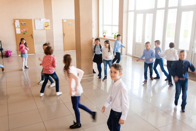 Grupo de escolares corriendo felices en el descanso. Desenfoque de movimiento sobre la actividad física