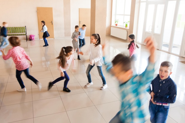 Grupo de escolares corriendo felices en el descanso. Desenfoque de movimiento sobre la actividad física