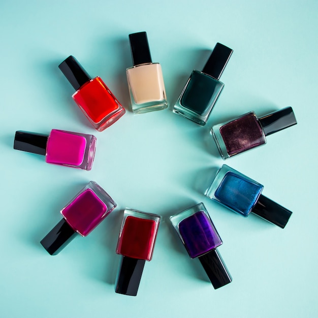 Foto grupo de esmaltes de uñas de colores brillantes sobre fondo azul conjunto de cosméticos decorativos para el cuidado del cuerpo