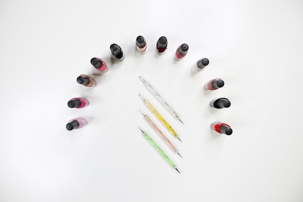 Grupo de esmaltes de uñas brillantes aislados en blanco y herramientas para hacer manicura