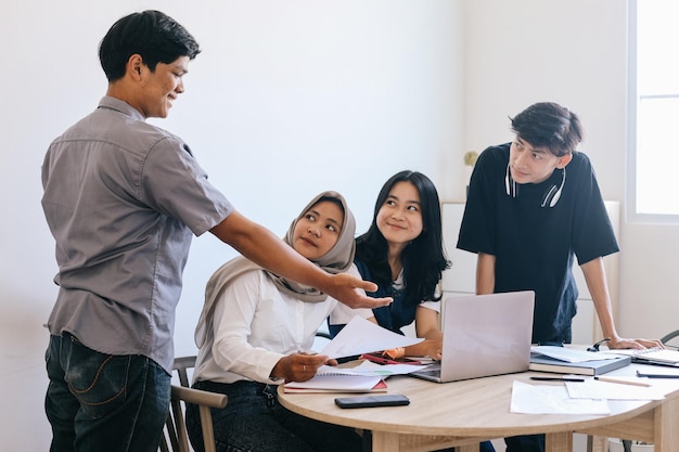 Grupo de estudiantes asiáticos estudiando juntos en el aula usando una computadora portátil