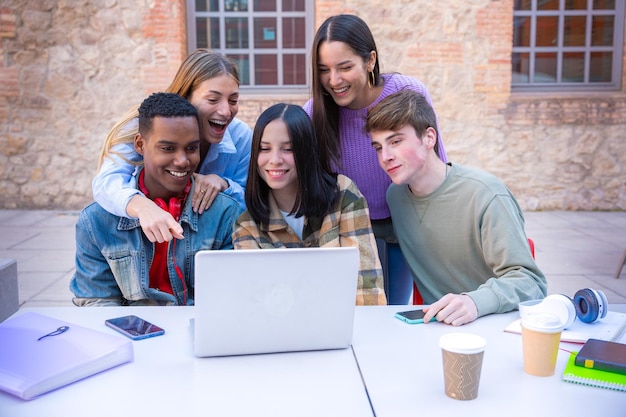 Un grupo de estudiantes con computadoras portátiles se sientan cerca del campus y se comunican