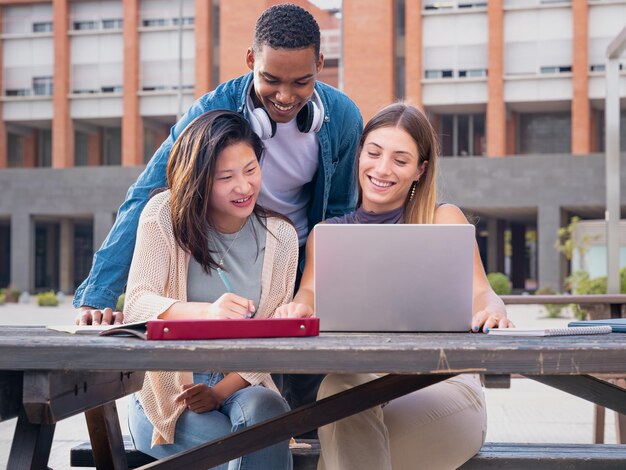 Un grupo de estudiantes con computadoras portátiles se sientan cerca del campus y se comunican