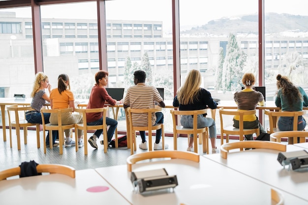 Foto grupo de estudiantes estudiando frente a la ventana de la biblioteca universitaria