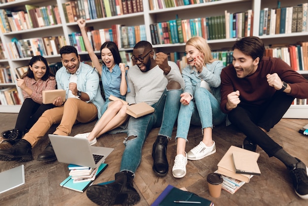 Grupo de estudiantes étnicos multiculturales en biblioteca.