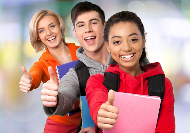 Foto grupo de estudiantes graduados mostrando los pulgares hacia arriba en el fondo borroso