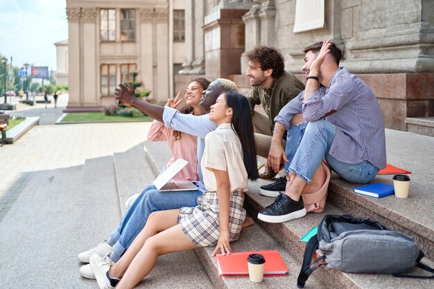 Grupo de estudiantes hablando en un enlace de video sentados en los escalones