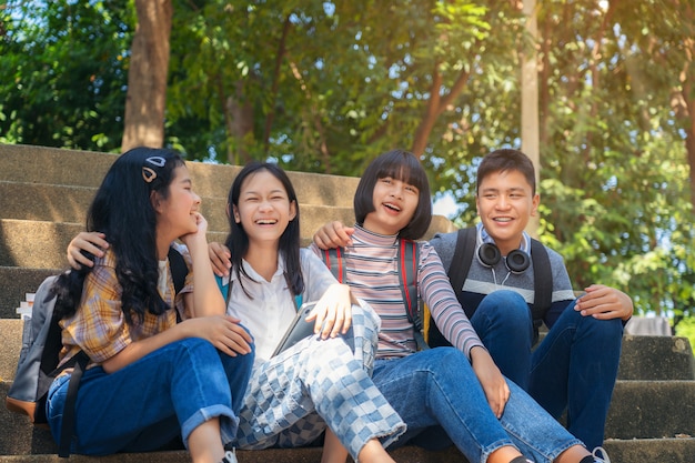 Grupo de estudiantes jóvenes y educación libro de lectura en el parque de la ciudad