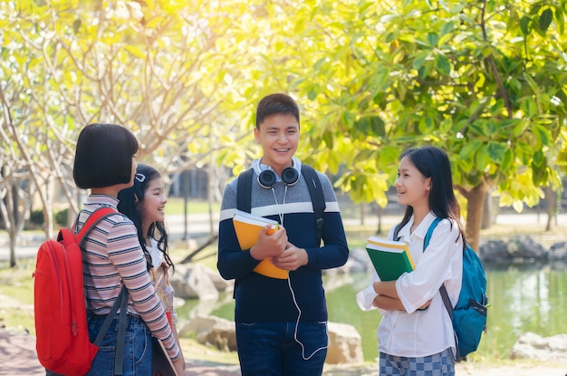 Grupo de estudiantes jóvenes felices caminando al aire libre, concepto de libro de estudiantes jóvenes diversos al aire libre