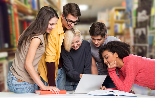 Grupo de estudiantes con laptop y libro haciendo lecciones.