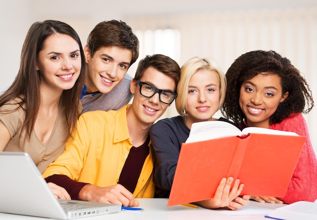 Grupo de estudiantes con laptop y libro haciendo lecciones.