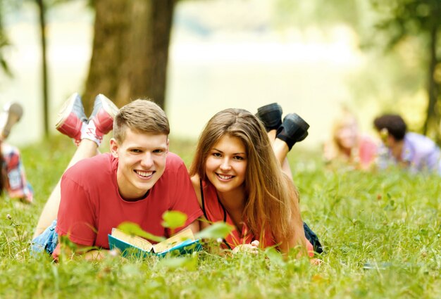 grupo de estudiantes con libros en el parque en un día soleado