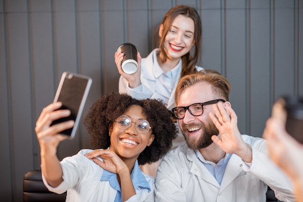 Grupo de estudiantes de medicina divirtiéndose fotografiando con teléfonos durante la pausa para el café en el aula