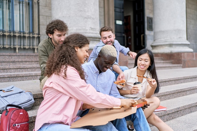 Grupo de estudiantes mirando una pizza caliente en una caja.