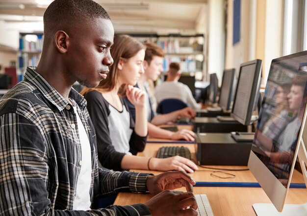 Grupo de estudiantes que usan computadoras en la biblioteca de la universidad