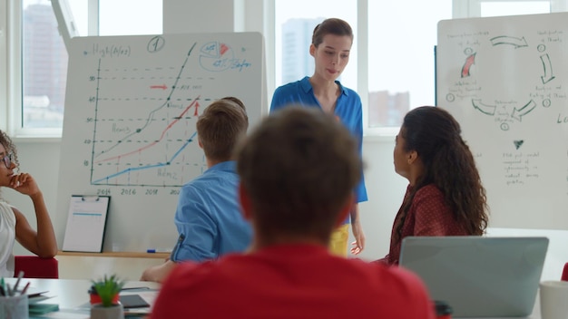 Un grupo de estudiantes en un salón de clases, uno de ellos está hablando a un grupo de estudiantes.