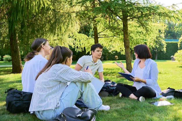 Grupo de estudiantes de secundaria con profesora en el césped del campus