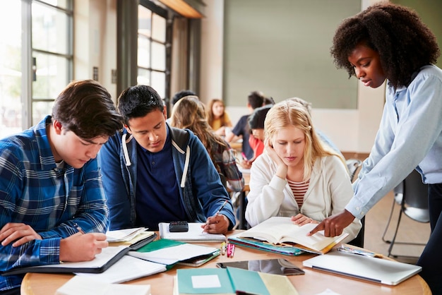 Grupo de estudiantes de secundaria con profesora trabajando en el escritorio