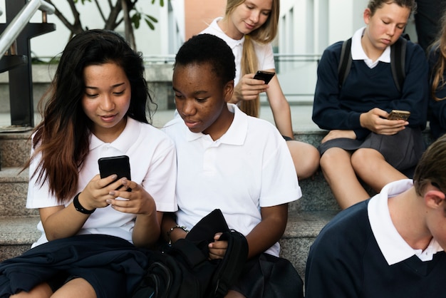 Grupo de estudiantes sentados en las escaleras y utilizando dispositivos digitales.