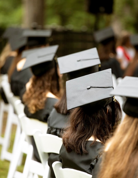 Foto un grupo de estudiantes se sientan en una ceremonia de graduación enfocada en el birrete