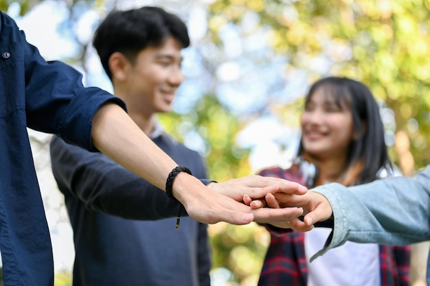 Un grupo de estudiantes universitarios asiáticos felices juntando sus manos celebrando el éxito