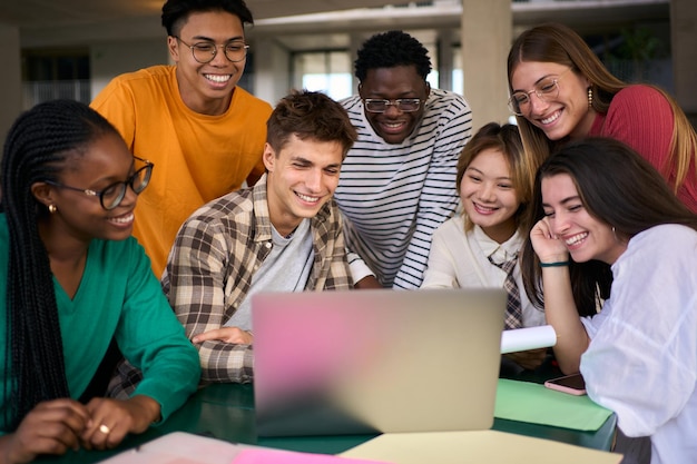 Un grupo de estudiantes universitarios concentrados usando una computadora portátil en la cafetería del campus.