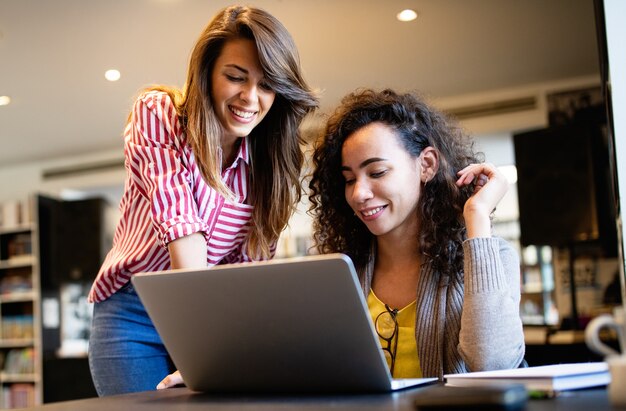 Grupo de estudiantes universitarios felices que estudian en la biblioteca de la escuela