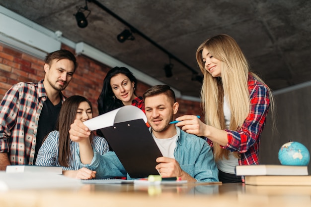 Grupo de estudiantes universitarios mirando juntos en la computadora portátil. Personas con información de búsqueda informática en internet, trabajo en equipo, proyecto conjunto