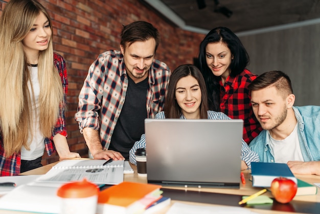 Grupo de estudiantes universitarios se prepara para los exámenes juntos. Personas con información de búsqueda de laptop en internet