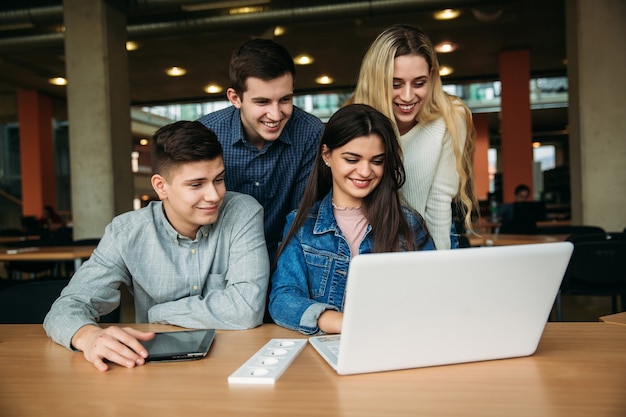 Grupo de estudiantes universitarios que estudian en la biblioteca de la escuela, una niña y un niño están usando una computadora portátil y