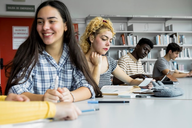 Grupo de estudiantes universitarios que estudian juntos en una biblioteca