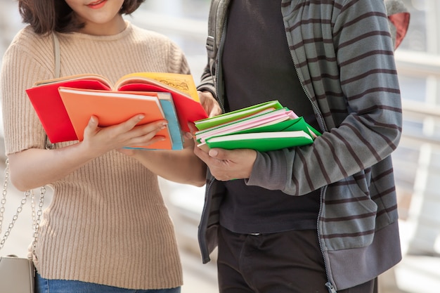 Grupo de estudiantes universitarios que leen y que tienen una discusión al aire libre