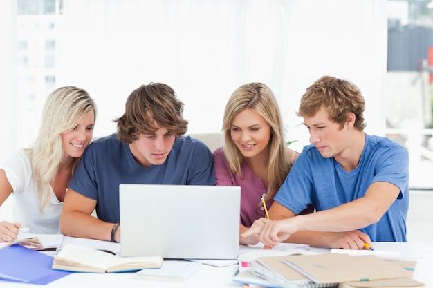 Un grupo de estudiantes usa una computadora portátil para responder sus preguntas