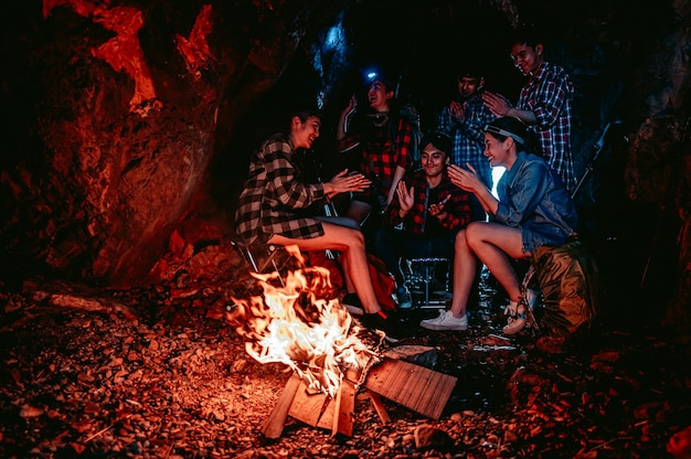 Un grupo de excursionistas encendió una fogata para cocinar comida en una cueva por la noche Aventura y camping