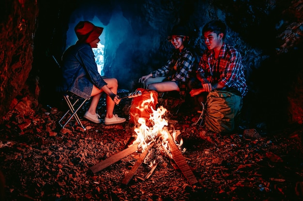 Un grupo de excursionistas encendió una fogata para cocinar comida en una cueva por la noche Aventura y camping
