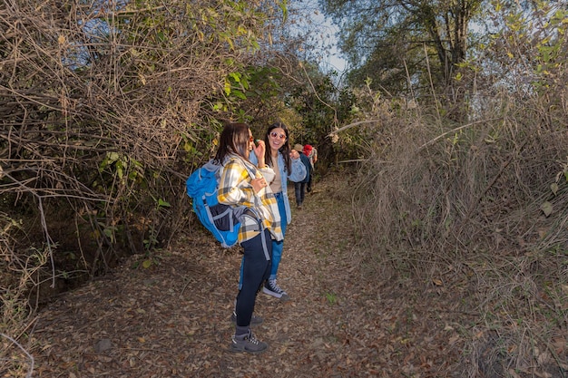 Un grupo de excursionistas, hombres y mujeres de diferentes edades, caminan por un sendero en medio de la naturaleza con el concepto de ecoturismo