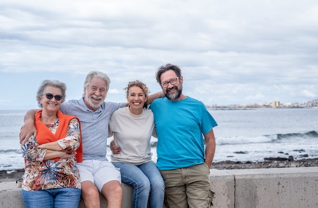 Grupo de familia multigeneracional sentada y abrazándose en el mar. Concepto de amor y familia
