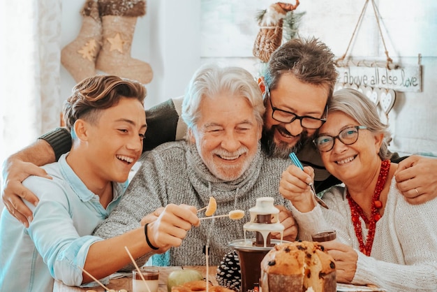 Grupo familiar celebra juntos o almoço de natal à mesa comendo e se divertindo na amizade homens e mulheres de idades mistas curtindo o feriado de natal em casa gerações jovens e idosas